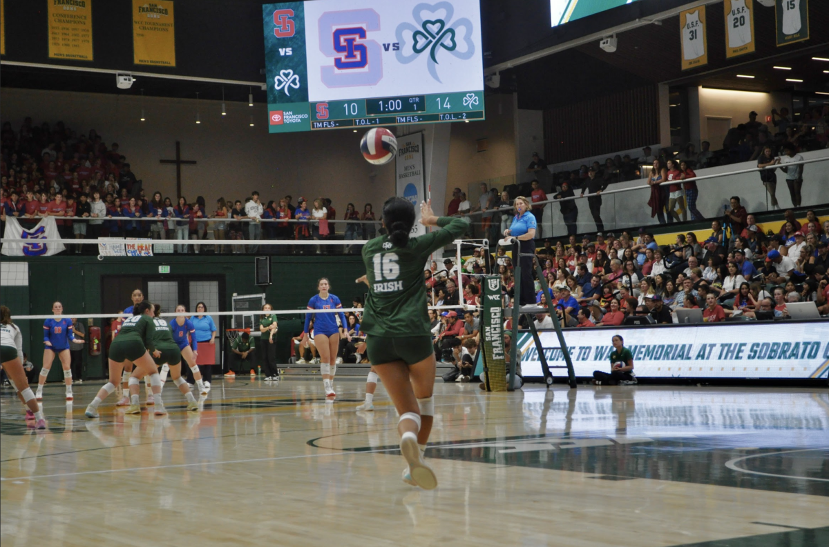 Livy Tangaan ‘25 tosses the ball in the air to serve.